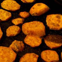 Oven baked sweet potato slices with seasoning on baking sheet