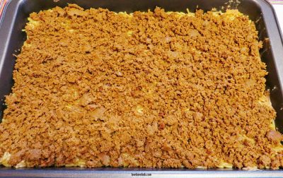 Taco meat layered on rice, refried beans, and pizza crust in a casserole dish