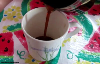 Coffee pouring from IMUSA espresso carafe into a mug