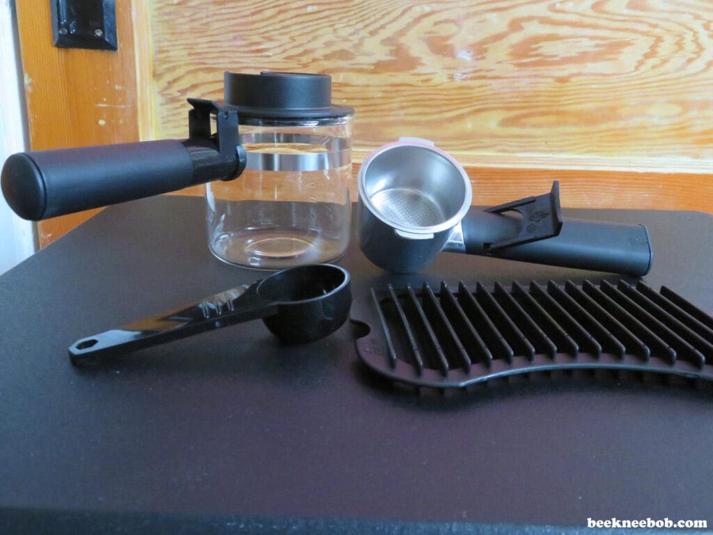Removable parts of the IMUSA espresso maker including carafe, drip tray, coffee scoop, and filter basket