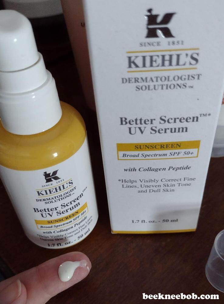 Bottle of Kiehl's Better Screen UV Serum Sunscreen with box and a sample of product on fingertip