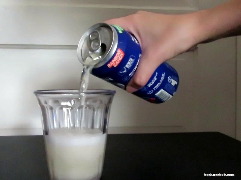 Can of Bucked Up Rainbow Candy Protein Soda pouring clear liquid into a cup