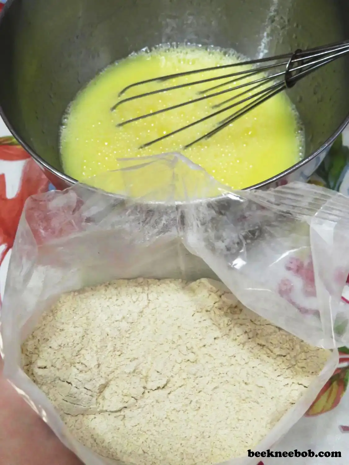 bowl of eggs, water, and oil with whisk behind an open package of dry quick bread mix
