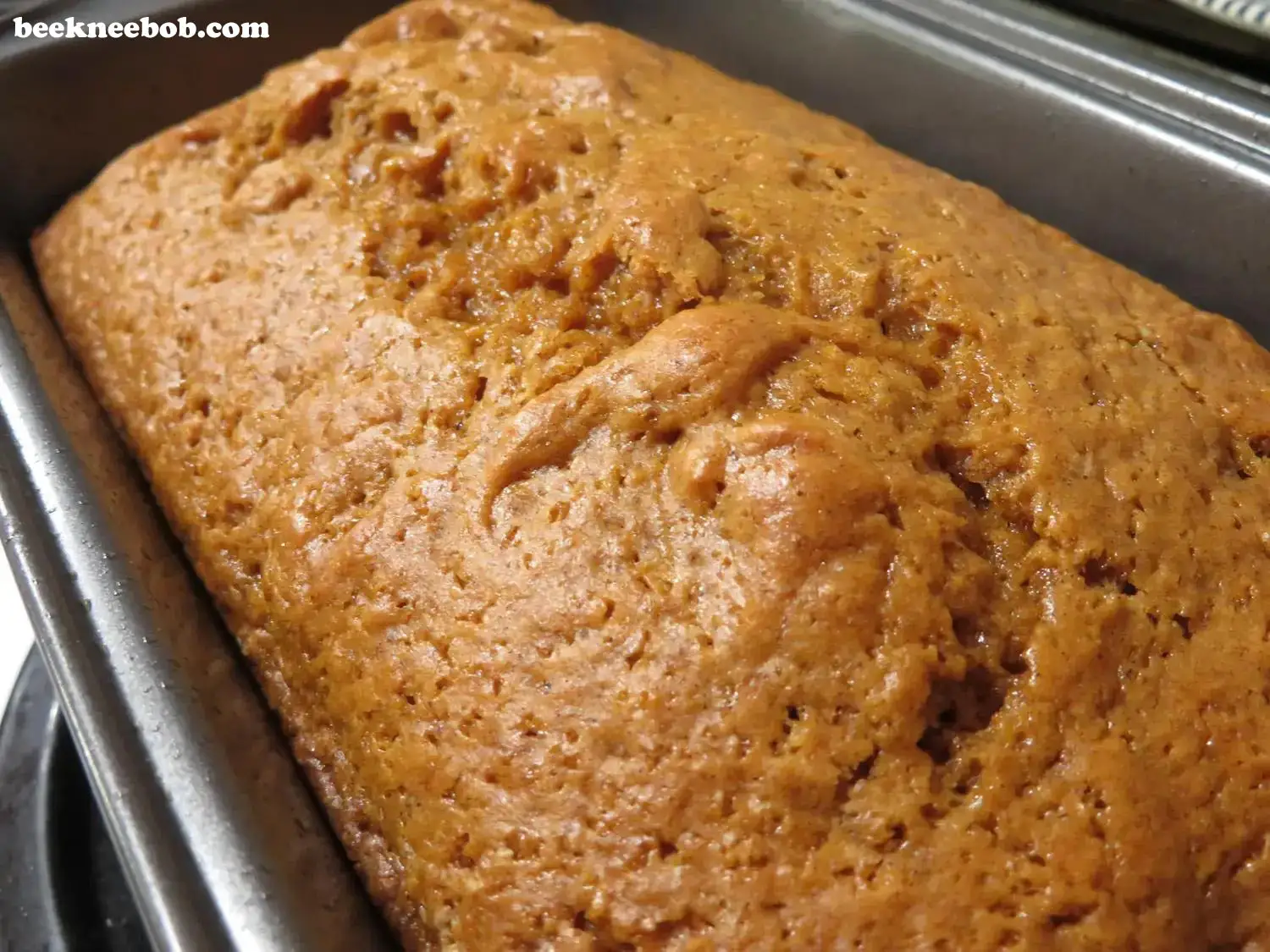 angled close up of baked pumpkin quick bread in loaf pan