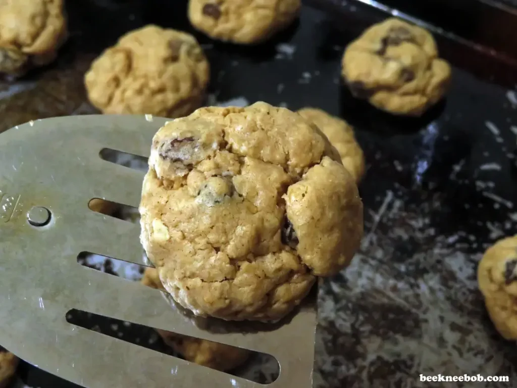 close up of oatmeal raisin cookie lifted from baking sheet with a spatula