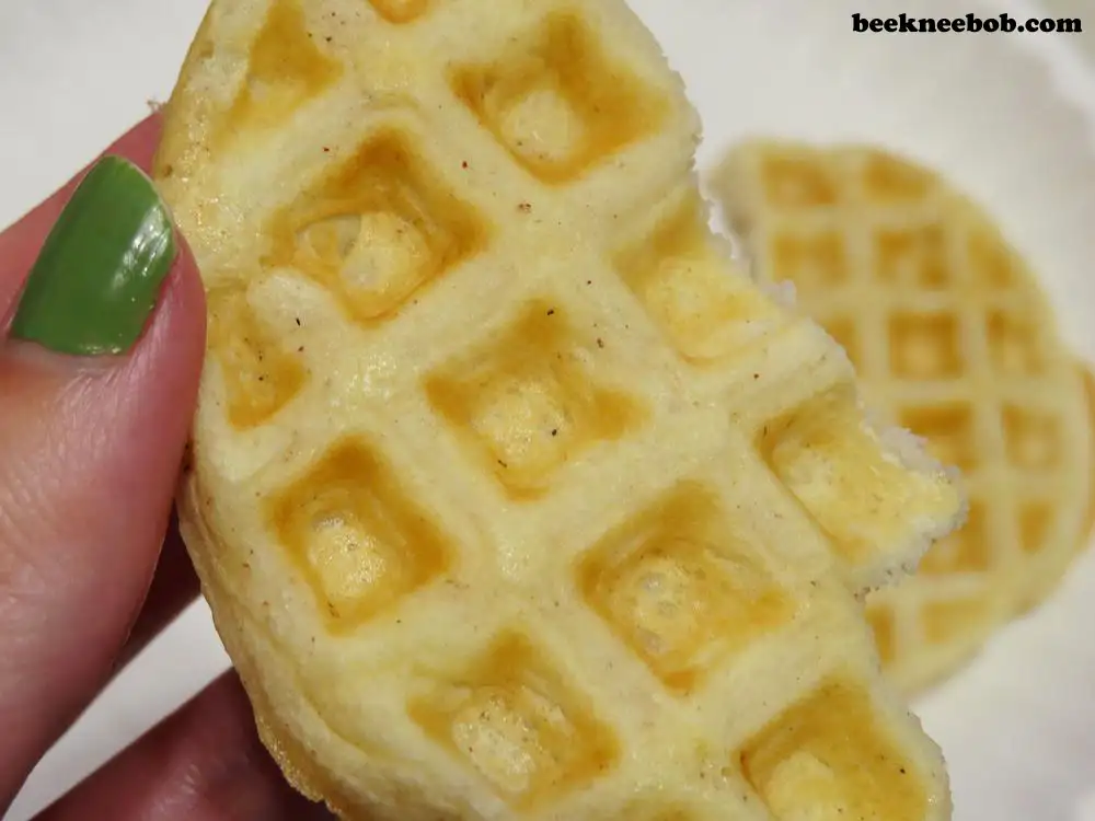 Close up of a hand holding a torn half of a mini waffle