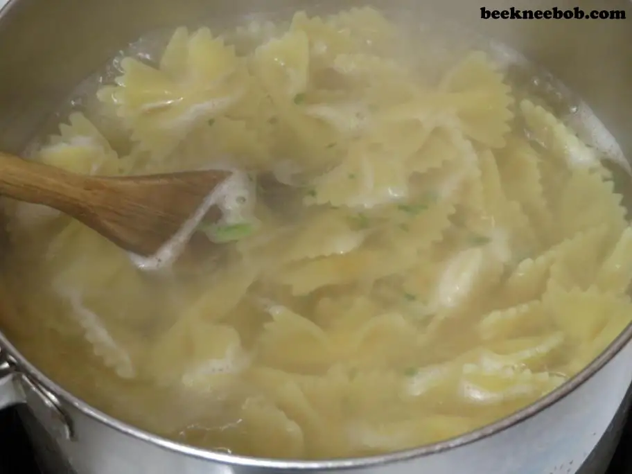 Boiling a pot of bowtie pasta according to package instructions for a 20-minute meal.