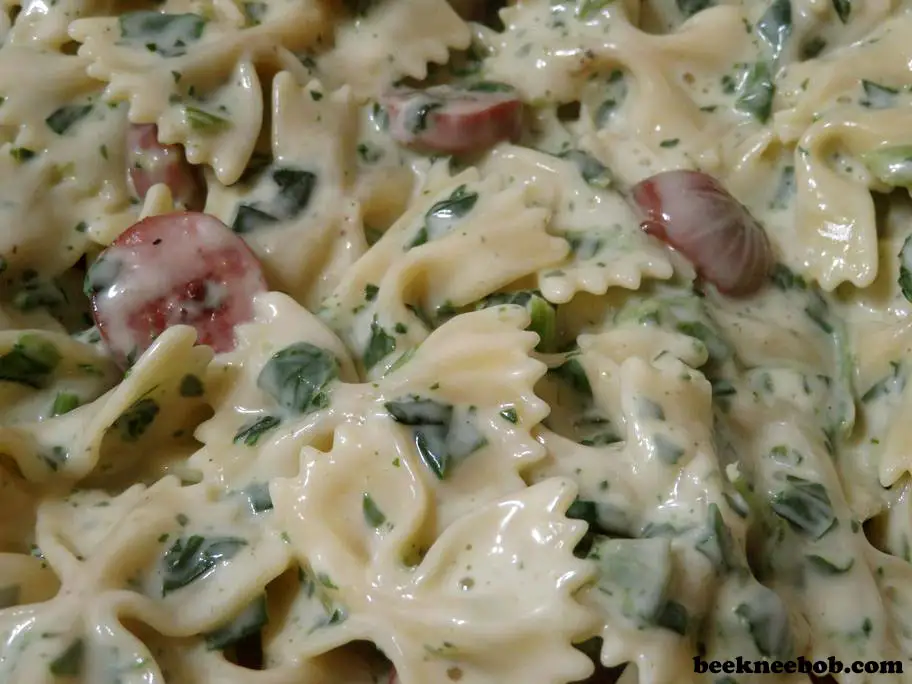 Finished 4-ingredient pasta dish showing wilted spinach and browned sausage rounds.