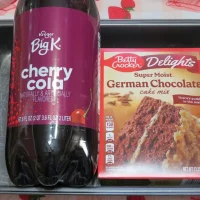 An empty cake pan holding a 2-liter bottle of cherry cola and a box of German chocolate cake mix for Chocolate Cherry Soda Cake recipe