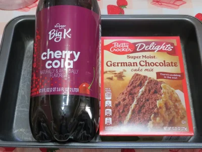 An empty cake pan holding a 2-liter bottle of cherry cola and a box of German chocolate cake mix for Chocolate Cherry Soda Cake recipe