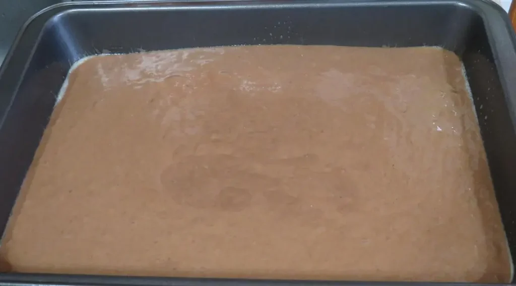 chocolate cherry cola soda batter poured into a 13 by 9 inch cake pan, ready for baking into a chocolate cherry soda cake