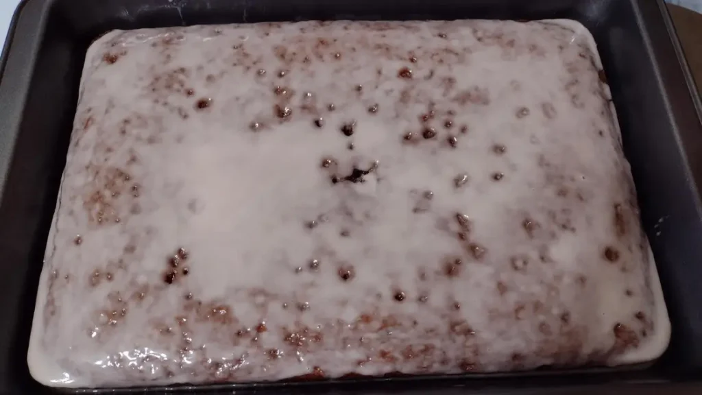 powdered sugar glaze poured over a porous 2-ingredient chocolate cherry cola soda cake