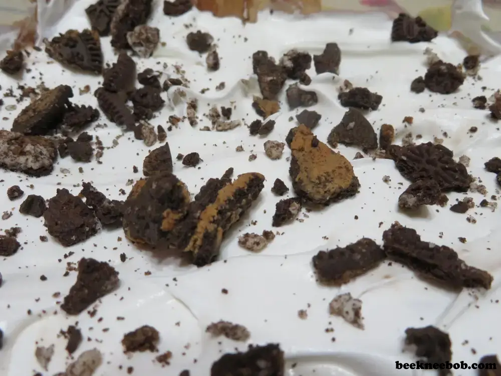 close up of peanut butter oreo dirt pudding with crushed sandwich cookies on top of a thick layer of whipped topping