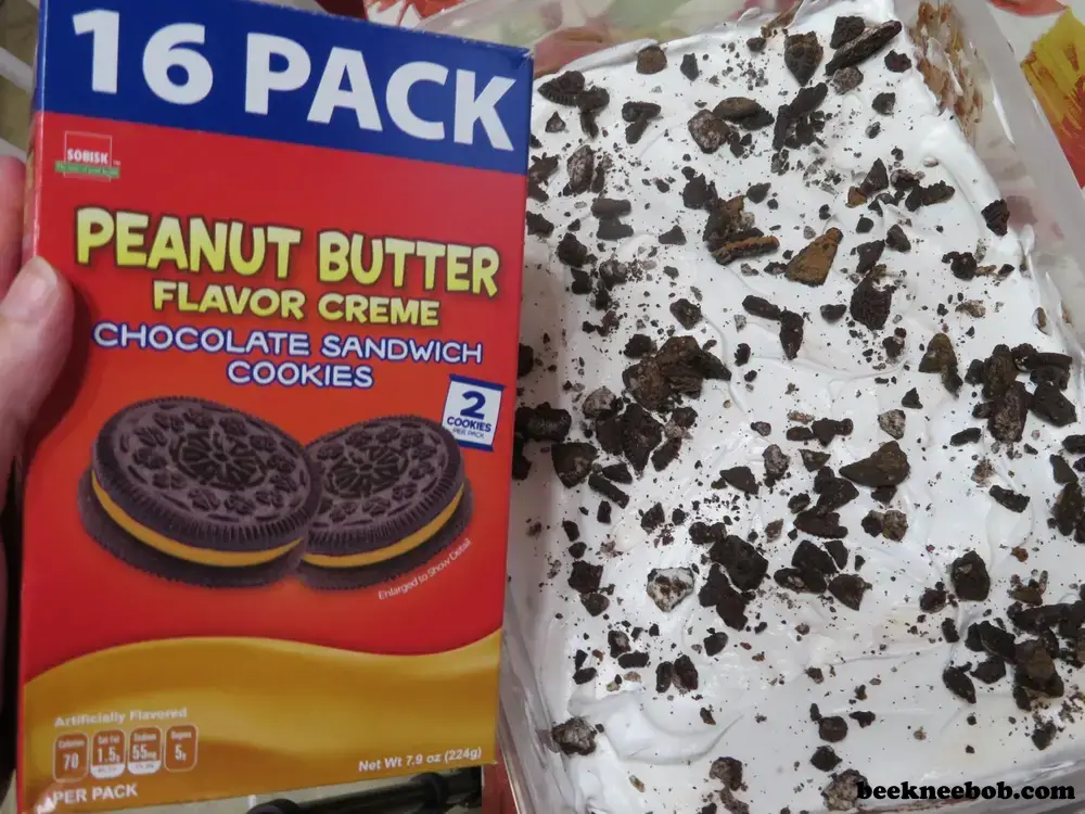 a box of peanut butter flavored chocolate sandwich cookies by Sobisk held next to a finished peanut butter cookie dirt pudding