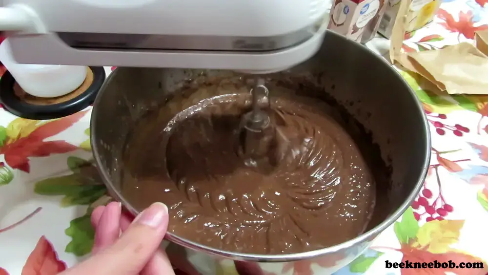 preparing chocolate and vanilla pudding in a stainless bowl using a hand mixer